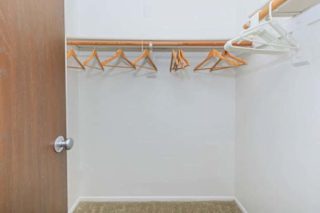 A white wall with a brown door and a coat rack with five hangers.