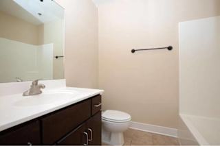 A white toilet sits in a bathroom next to a sink.