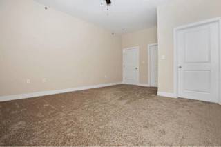 A room with a carpeted floor and three doors.