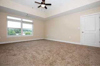 A room with a ceiling fan and carpeted floor.