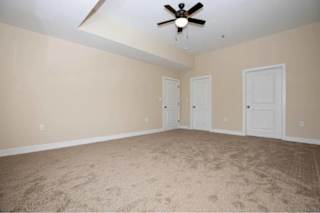 A room with a ceiling fan and carpeted floor.