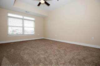 A room with a carpeted floor and a ceiling fan.