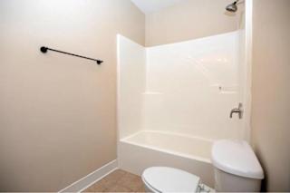 A white toilet sits next to a white bathtub in a small bathroom.