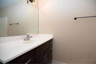 A white sink with a silver faucet and a mirror above it.