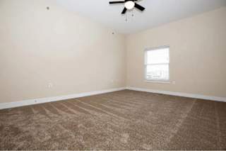A room with a carpeted floor and a ceiling fan.