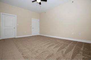 A room with a carpeted floor and a ceiling fan.