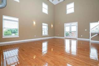 A spacious room with wooden floors and windows.