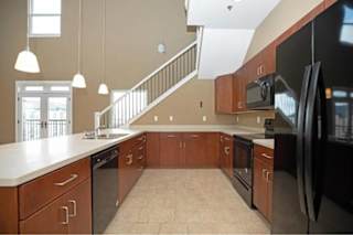 A kitchen with a black refrigerator and wooden cabinets.