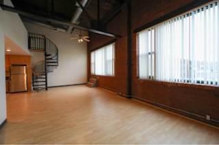 A large empty room with wooden floors and a spiral staircase.