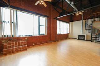 A large empty room with wooden floors and a spiral staircase.