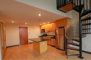 A kitchen with a black staircase on the right.
