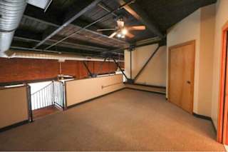 A room with a carpeted floor and a ceiling fan.