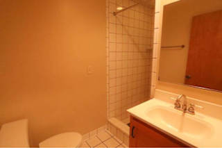 A bathroom with a toilet, sink, and tiled shower.
