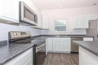 A kitchen with white cabinets and a black countertop.
