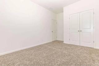 A room with a carpeted floor and two white doors.