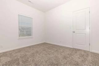 A room with a carpeted floor and a door.