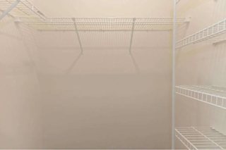 Empty white shelves in a refrigerator.