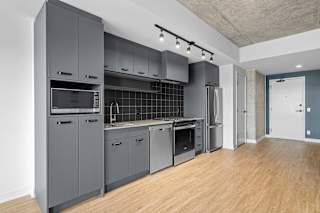 A modern kitchen with wooden floors and grey cabinets.
