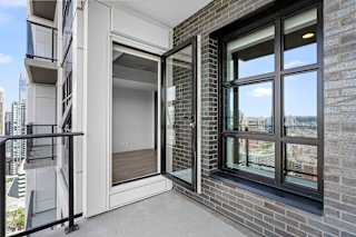 A balcony with a glass door and a black railing.