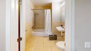 A bathroom with a white shower curtain and a white toilet.