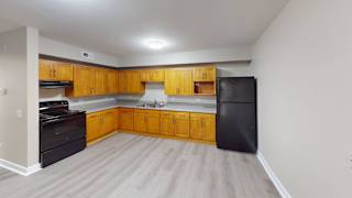 A kitchen with wooden cabinets and a black fridge.
