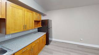 A kitchen with wooden cabinets and a black refrigerator.