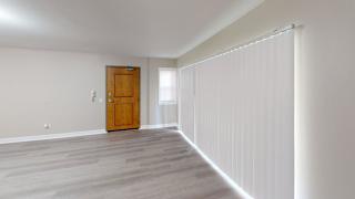 A room with a wooden door and a window with blinds.