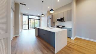 A modern kitchen with a white island and dark wood floors.