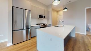 A modern kitchen with a stainless steel refrigerator and a white island.