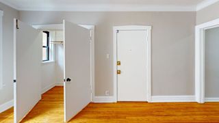 A room with white walls and wooden floors with two doors.