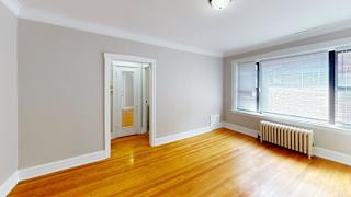 A room with wooden floors and a window with blinds.