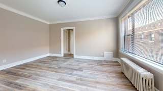 A room with wooden flooring and a window with blinds.