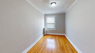 A room with a window and a radiator on the floor.