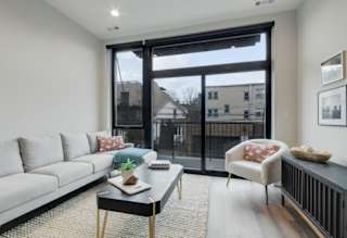 A living room with a grey couch, a black coffee table, and a chair with a red pillow.