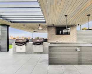 the outdoor patio has a tv and two bar stools
