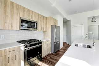 Modern kitchen with stainless steel appliances and wood cabinetry at Inwood at Renaissance Square Apartments, New Jersey