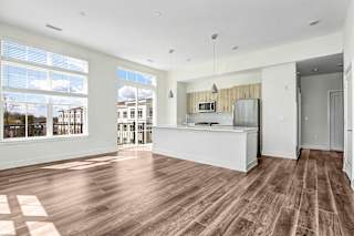 Open layout living space with kitchen island and balcony access at Inwood at Renaissance Square Apartments, Marlton