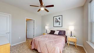 A bedroom with a bed, nightstand, and a ceiling fan at The Slate, Jeffersonville, 47130
