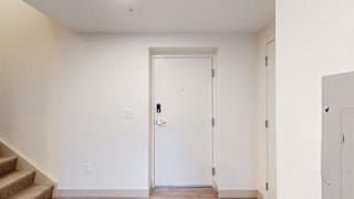 A white door with a black handle is in a room with white walls.