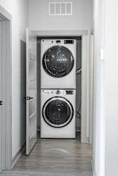 A white front loading washing machine is in a doorway at Arbour Place Apartments, Jeffersonville, IN