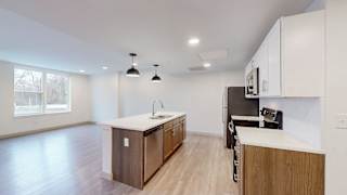 A kitchen with a refrigerator, sink, and cabinets.