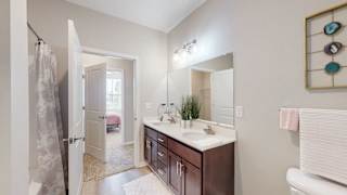 A bathroom with a white toilet, a sink with a mirror, and a shower with a curtain at The Slate, Jeffersonville, 47130