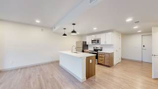 A kitchen with a white counter top and wooden floors.