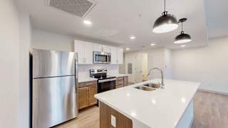 A modern kitchen with a stainless steel refrigerator and a white countertop.