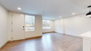 A room with a white door and a window with a view of a tree and a building outside.