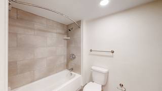A white toilet sits next to a white bathtub in a bathroom.