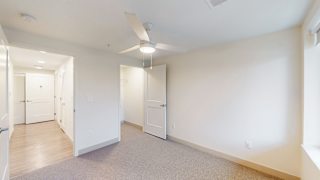 A spacious room with a ceiling fan and carpeted floor.