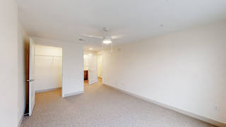 A large, empty room with a door on the left and a window on the right.