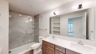 A bathroom with a white sink, toilet, and a glass shower stall.