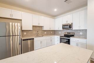 White kitchen with stainless steel appliances and island at Allure Apartments, Indiana